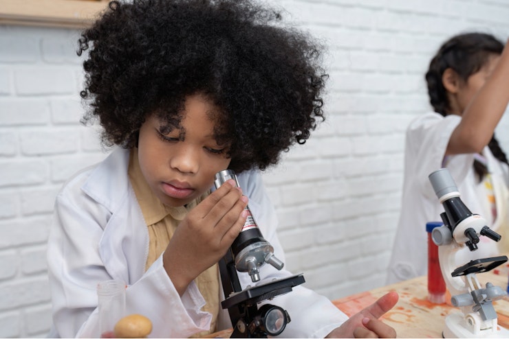 Young girl looking into a microscope